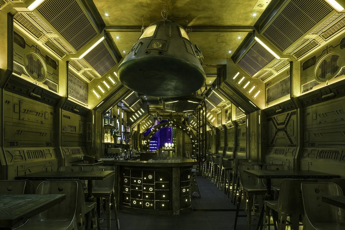 GATE Lan Kwai Fong interior — a spaceship-themed cocktail bar with a capsule suspended above the bar and illuminated cockpit panels lining the walls